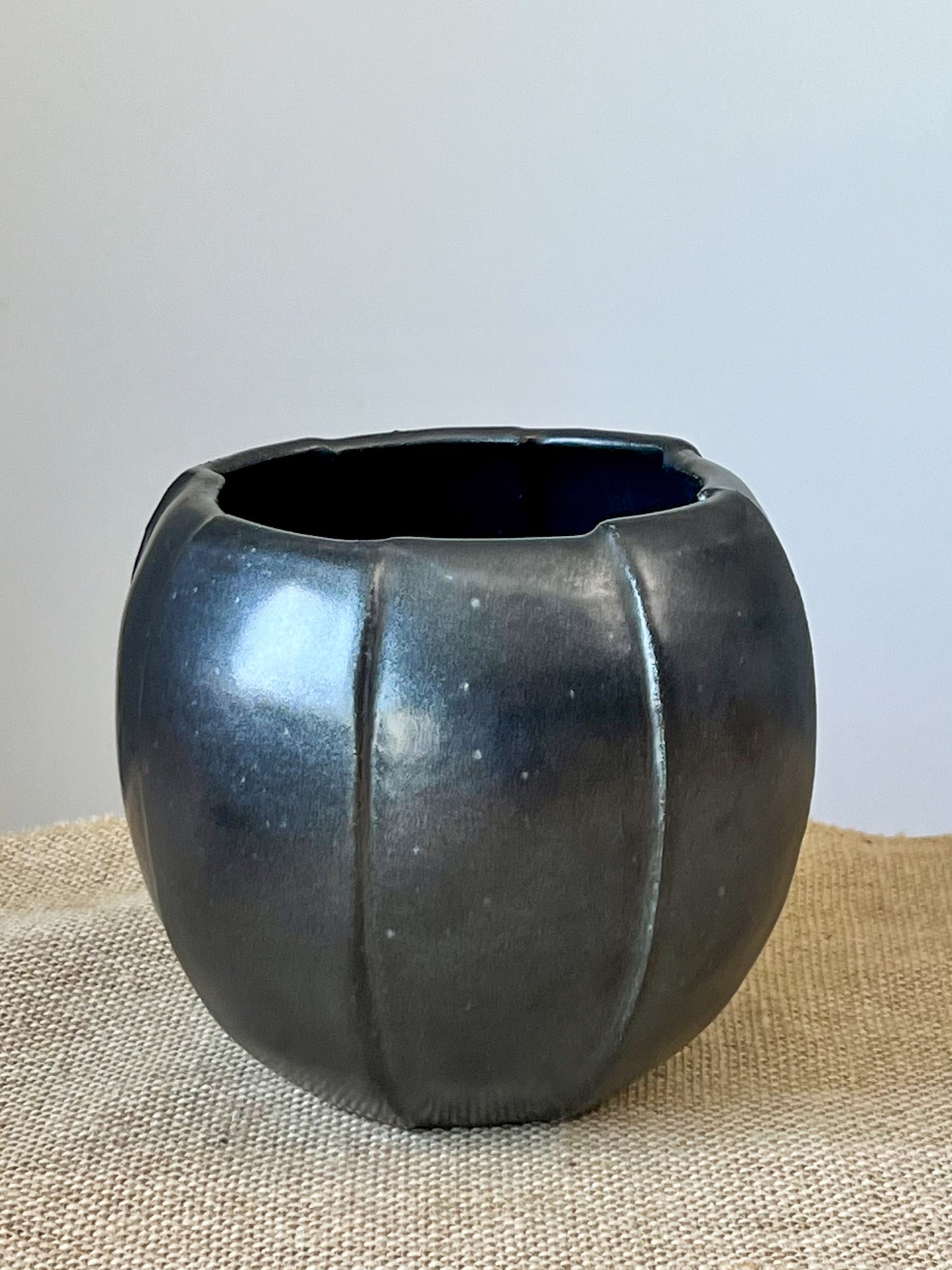 Wheel thrown vase using stoneware clay. After wheel throwing the vase was then cut into sections and reattached creating an interesting offset design. Finished with a matte black glaze.