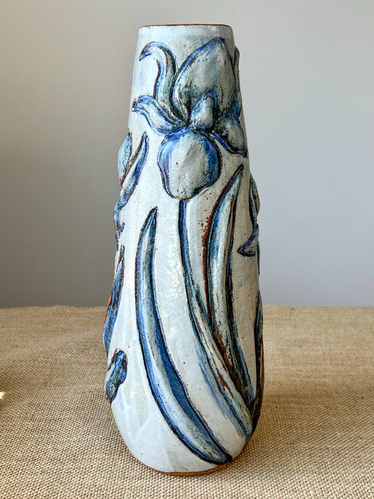 Wheel thrown vase using stoneware clay. Elegantly tall vase with hand carved irises highlighted in a cobalt oxide and then covered with a white glaze.