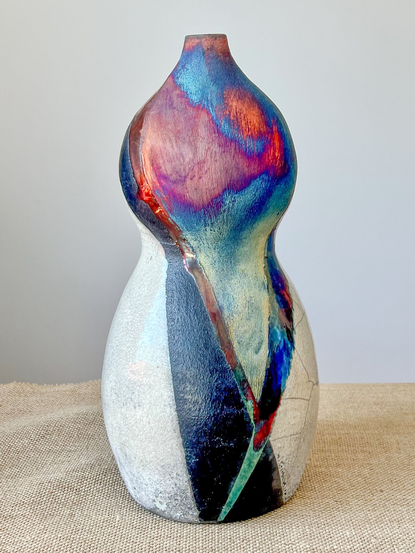 Wheel thrown using stoneware clay. The rainbow, crackle white and black finish is achieved through the Raku technique.