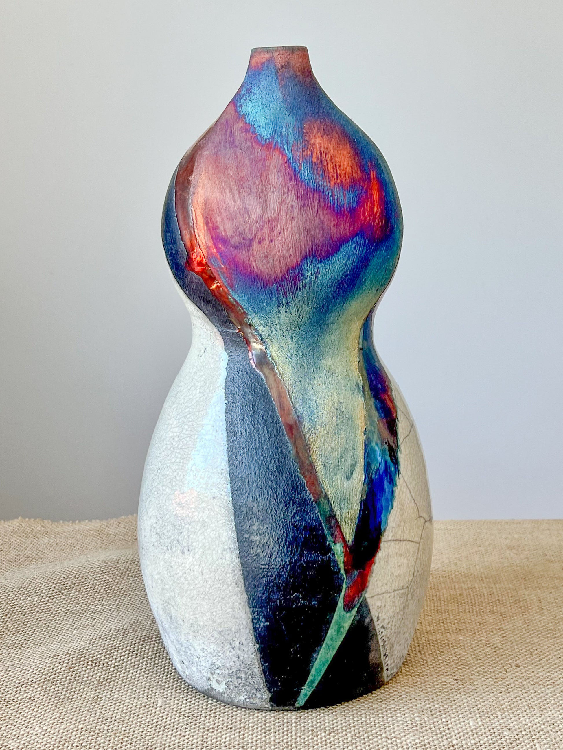 Wheel thrown using stoneware clay. The rainbow, crackle white and black finish is achieved through the Raku technique.