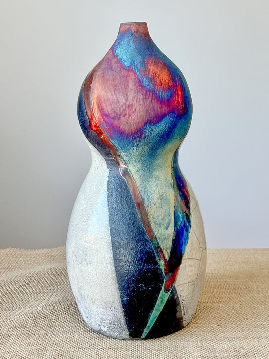 Wheel thrown using stoneware clay. The rainbow, crackle white and black finish is achieved through the Raku technique.