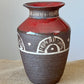 Wheel thrown vase using dark brown clay. Sunset pattern is made using the Mishima process of inlaying white clay into the hand carved design. The body is unglazed  with a band of red glaze. The interior is also red.