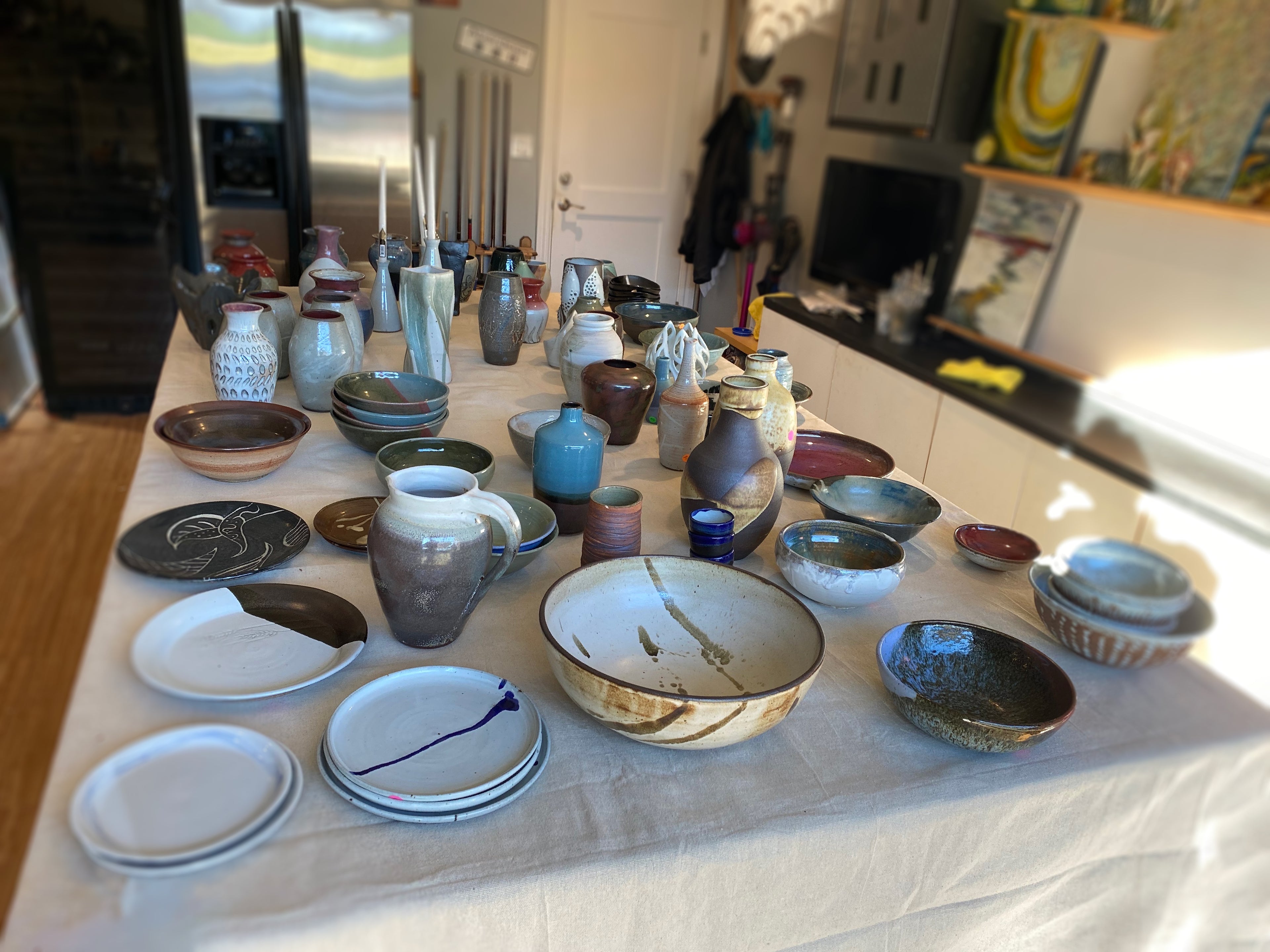 A variety of hand thrown ceramics including plates, bowls, vases, and sculptures. Glazed with white, brown, blues, and reds mainly.